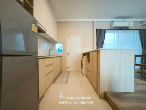 Modern kitchen with wooden cabinetry, stainless steel appliances, and adjacent dining area