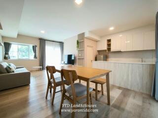 Modern open-plan living room and kitchen with wooden flooring and neutral furnishings