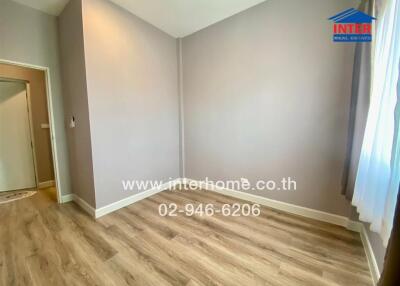 Empty bedroom with wooden floor and window with curtains.