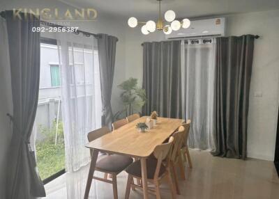 Bright dining area with wooden table and chairs next to large windows