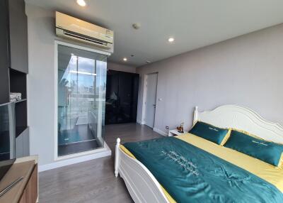 Modern bedroom with a bed, air conditioning, and a glass door leading to a balcony