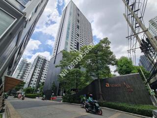 Exteriors of a tall modern apartment building on a bustling urban street