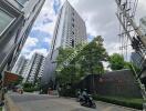 Exteriors of a tall modern apartment building on a bustling urban street