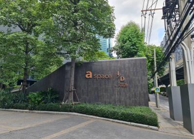 Exterior view of a building entrance with greenery and signage