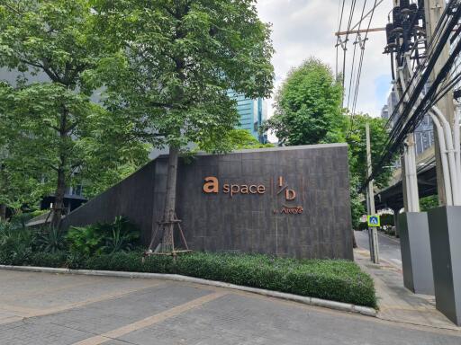 Exterior view of a building entrance with greenery and signage