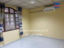 Empty bedroom with tiled floor, curtain, window, and air conditioner