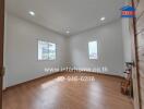 Spacious bedroom with wooden flooring and white walls