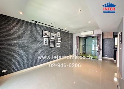 Spacious living room with modern brick accent wall and glossy tiled flooring.