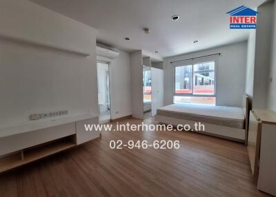 Spacious bedroom with a large window, wooden flooring, and a built-in air conditioning unit.