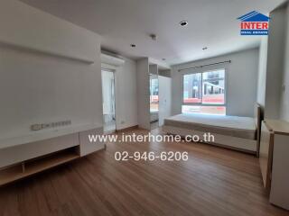 Spacious bedroom with a large window, wooden flooring, and a built-in air conditioning unit.