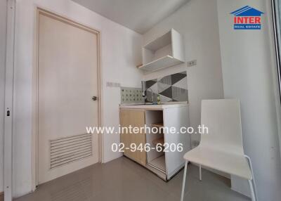 Compact kitchen area with sink, storage cabinets, and a white chair