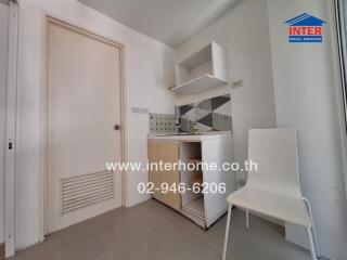 Compact kitchen area with sink, storage cabinets, and a white chair