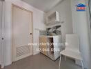 Compact kitchen area with sink, storage cabinets, and a white chair