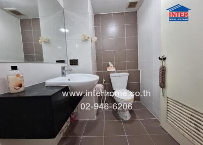 Modern bathroom with toilet, sink, mirror, and tiled walls