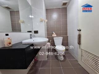 Modern bathroom with toilet, sink, mirror, and tiled walls