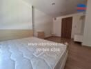 Bedroom with wooden floor, bed, and a partially visible chair