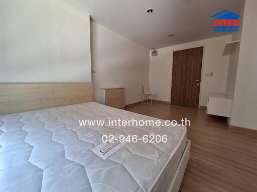 Bedroom with wooden floor, bed, and a partially visible chair