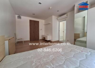 Bedroom with mattress, air conditioner, and wall-mounted desk