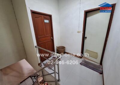 Interior hallway of a residential property near stairs with two closed doors and a basket