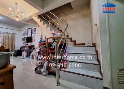 Photo of a living area with a staircase, chandelier, and various furnishings