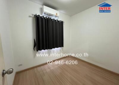 Bedroom with wooden flooring and a window with dark curtains