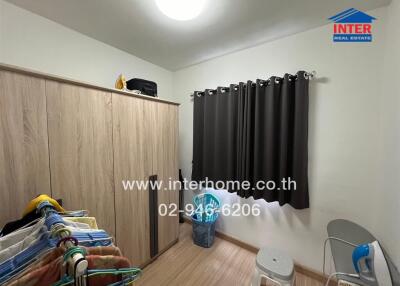 Small bedroom with wardrobe, clothes rack, and dark curtains