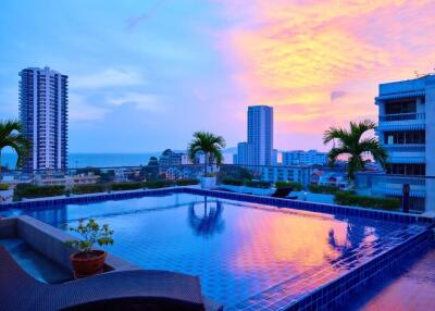 Rooftop pool with city and ocean view during sunset