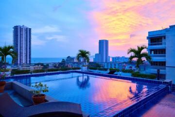 Rooftop pool with city and ocean view during sunset