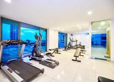 Well-equipped gym with modern exercise machines and large windows.