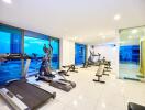 Well-equipped gym with modern exercise machines and large windows.