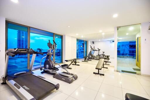 Well-equipped gym with modern exercise machines and large windows.