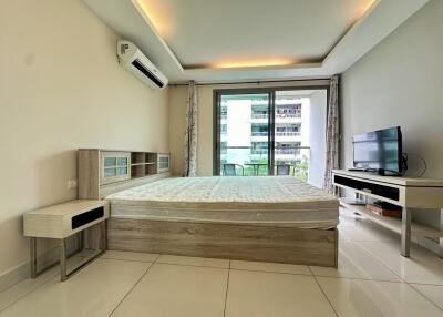 Modern bedroom with balcony view, featuring a bed, TV, and air conditioning unit