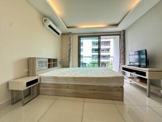 Modern bedroom with balcony view, featuring a bed, TV, and air conditioning unit