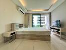 Modern bedroom with balcony view, featuring a bed, TV, and air conditioning unit