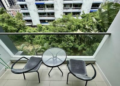 Balcony with chairs and table overlooking greenery