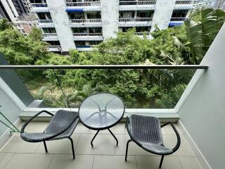 Balcony with chairs and table overlooking greenery