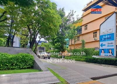 View of an apartment building with surrounding greenery and a street