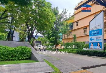 View of an apartment building with surrounding greenery and a street