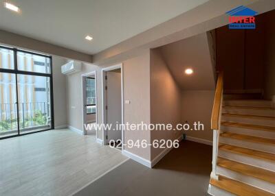 Spacious living room with large windows and wooden stairs