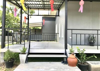 Front porch of a building with steps, potted plants, and decorations