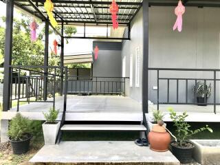 Front porch of a building with steps, potted plants, and decorations