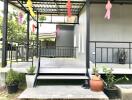 Front porch of a building with steps, potted plants, and decorations