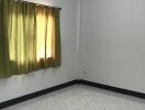 Empty bedroom with tiled floor and green curtains