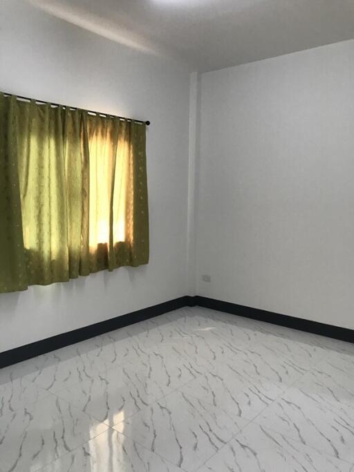 Empty bedroom with tiled floor and green curtains