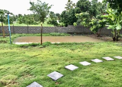 View of the backyard featuring a small pond surrounded by lush greenery