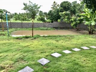 View of the backyard featuring a small pond surrounded by lush greenery