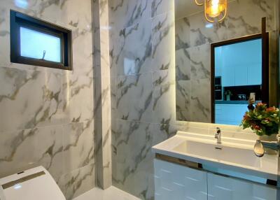 Modern bathroom with marble walls, pendant lights, and a vanity sink