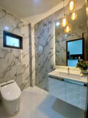 Modern bathroom with marble walls, pendant lights, and a vanity sink