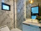 Modern bathroom with marble walls, pendant lights, and a vanity sink