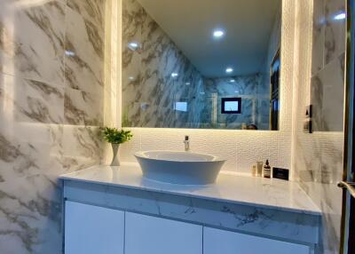 Modern bathroom with marble wall and illuminated mirror